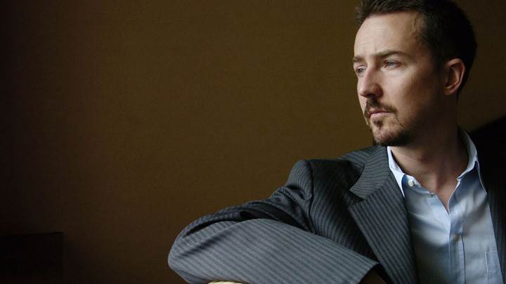 Edward Norton In Grey Coat Sitting Pose On Sofa